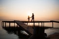 Silhouettes of people children on shore lake. Summer sunset on water. evening walk outdoor on bridge Royalty Free Stock Photo