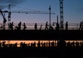 Silhouettes of people crossing bridge with sunset sky background