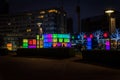 Silhouettes of people having fun at night while posing in front of cubes illuminated with different light colours in Chavasse Park Royalty Free Stock Photo