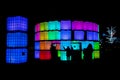 Silhouettes of people having fun at night while posing in front of cubes illuminated with different light colours in Chavasse Park Royalty Free Stock Photo