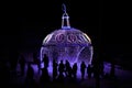 Silhouettes of people and a huge glowing Christmas ball on the street at night. Details of the street decoration for the New Year