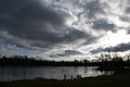 Silhouettes of people near the lake against the blue sky covered with dark low clouds Royalty Free Stock Photo