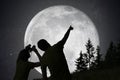 Silhouettes of people observing stars in night sky. Moon in background. Royalty Free Stock Photo