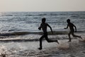 Silhouettes of people play in the waves in the Bekal beach