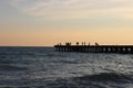 Silhouettes of people, probably fishermen on the pier in the sea Royalty Free Stock Photo