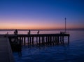 Silhouettes Of People Standing On A Pier At Sunset