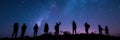 Silhouettes of people stargazing against a night sky