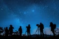 Silhouettes of people stargazing against a night sky