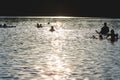 Silhouettes of people on a sunset lake background.Group of happy children having fun in summer lake or water