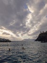 Manarola ITALY - 2 August 2023 - Silhouettes of people swimming in the Mediterranean sea at cloudy evening