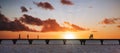 Silhouettes of people walking on a bridge at sunset Royalty Free Stock Photo