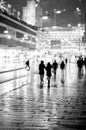 Silhouettes of people walking in rain in city street