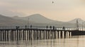 The silhouettes of the pier,boats,fishermen on the background of the mountains and Bay. Royalty Free Stock Photo