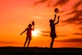 Silhouettes of playing boy with windmill and girl with ball in the nature