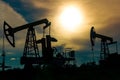 Silhouettes of pumpjacks on an oil wells against the background of an alarming sky