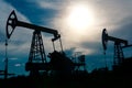 Silhouettes of pumpjacks on an oil wells against the background of an alarming sky