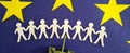 Silhouettes of refugees from paper fleeing military aggression against background of EU flag