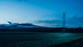Silhouettes of rural scenery, crops, mountains and high-voltage power poles Royalty Free Stock Photo