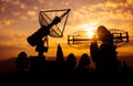 Silhouettes of satellite dishes or radio antennas against sunset sky. Space observatory