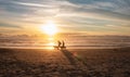 Silhouettes of senior couple with dogs walking along sand beach. Oregon shore beach sunset view with people walking by Royalty Free Stock Photo