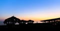 Silhouettes of small hovels with reed roofs and restaurant on the seashore at sunset