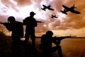 Silhouettes of soldiers with assault rifles and military airplanes patrolling