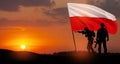 Silhouettes of soldiers with national flag on background of sunset. Polish Armed Forces.