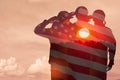 Silhouettes of soldiers with print of sunset and USA flag saluting on a background of light sky. Royalty Free Stock Photo