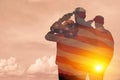 Silhouettes of soldiers with print of sunset and USA flag saluting on a background of light sky. Royalty Free Stock Photo