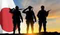 Silhouettes of a soldiers saluting on background of susnset with Japan flag