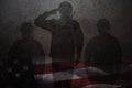 Silhouettes of soldiers saluting rusty on iron background with image of USA flag.