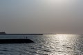 Silhouettes of stone breakwaters with person standing at the end, Umm Al Quwain, United Arab Emirates