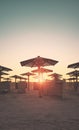 Silhouettes of sun umbrellas and windscreens on a beach at sunset, color toning applied