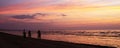 Silhouettes of three cyclists leaving along the coastline of the Baltic Sea at sunset in Jurmala