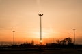 Silhouettes of three lampposts of street lighting form a perspective of a triangle against the sunset over the horizon Royalty Free Stock Photo