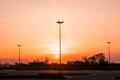 Silhouettes of three lampposts of street lighting form a perspective of a triangle against the sunset over the horizon Royalty Free Stock Photo