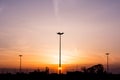 Silhouettes of three lampposts of street lighting form a perspective of a triangle against the sunset over the horizon Royalty Free Stock Photo