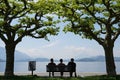 Silhouettes of three persons sitting on a bench.