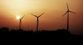 The silhouettes of three wind turbines at sunset. Royalty Free Stock Photo