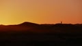 Silhouettes of tourist couple enjoying the colorful sunrise in the sand dunes of Erg Chebbi near Merzouga in Morocco, Africa. Royalty Free Stock Photo