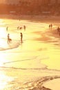 Silhouettes of tourists in the surf line in the orange rays of sunset at Praia da Rocha