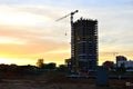 Silhouettes of tower cranes constructing a new residential building at a construction site against sunset background Royalty Free Stock Photo