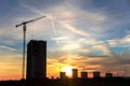 Silhouettes of tower cranes constructing a new residential building at a construction site against sunset background. Royalty Free Stock Photo