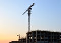 Silhouettes of tower cranes constructing a new residential building at a construction site against sunset background. Renovation Royalty Free Stock Photo