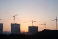 Silhouettes of tower cranes constructing a new residential building at a construction site against sunset background. Renovation Royalty Free Stock Photo