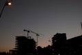 Silhouettes of tower cranes at the construction site of high-rise buildings at sunset Royalty Free Stock Photo