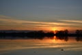 Silhouettes of trees at sunset on the lake in winter. Reflection of the sunset sky and trees in the quiet surface of the water. Royalty Free Stock Photo