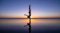 Silhouettes of two acrobats performing a handstand pose at sunset reflected on water Royalty Free Stock Photo