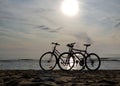 Silhouettes two bicycles parked in the sand beach on a bright sunny summer day Royalty Free Stock Photo