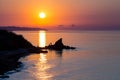 Silhouettes of two fishermen who came by bicycle to a fishing spot, on a cliff forming a peninsula